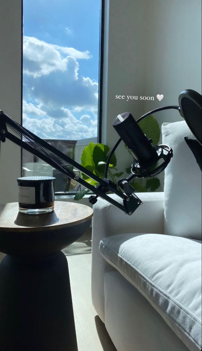 a desk lamp sitting on top of a wooden table next to a white couch in front of a window