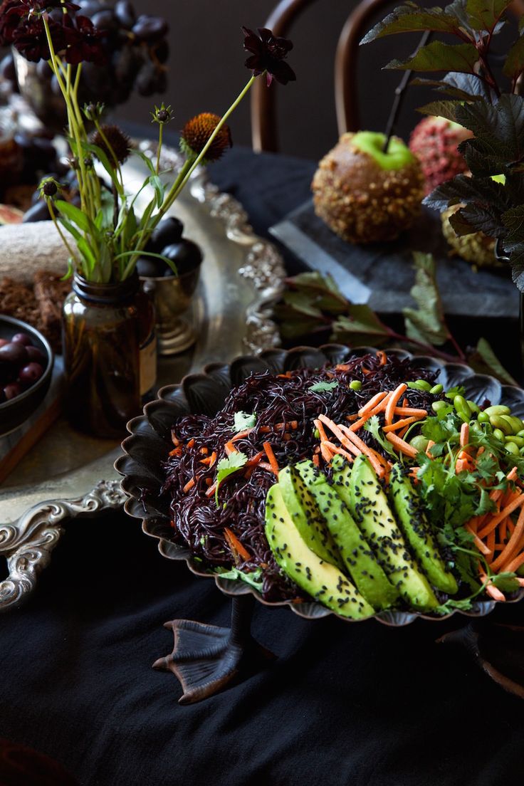 a bowl filled with carrots, lettuce and avocado on top of a table