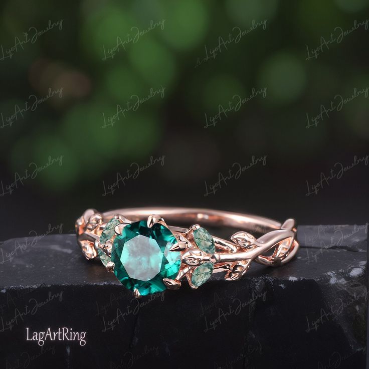 a ring with green stones and leaves on it, sitting on top of a rock