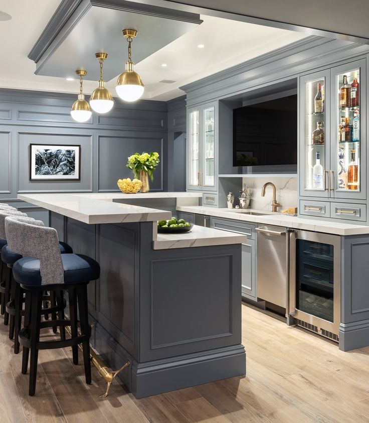 a kitchen with gray cabinets and white counter tops, blue bar stools, gold chandelier