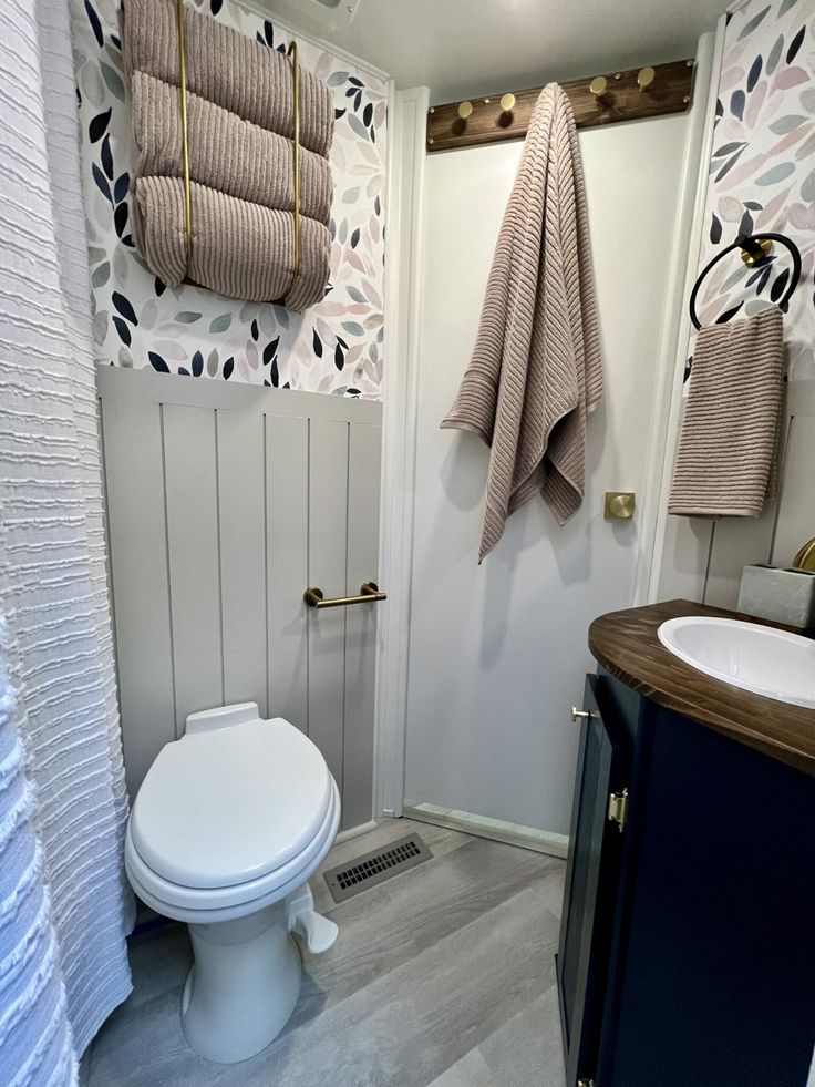 a white toilet sitting in a bathroom next to a wooden counter top under two towels