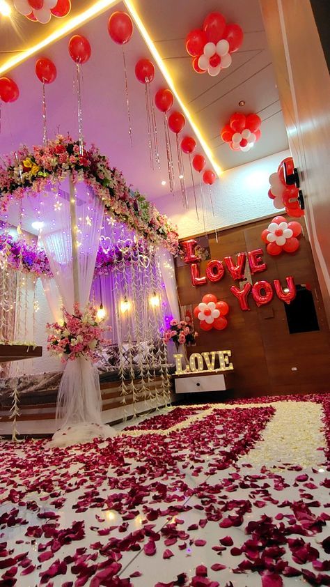 a wedding stage decorated with red and white flowers, balloons and streamers on the ceiling