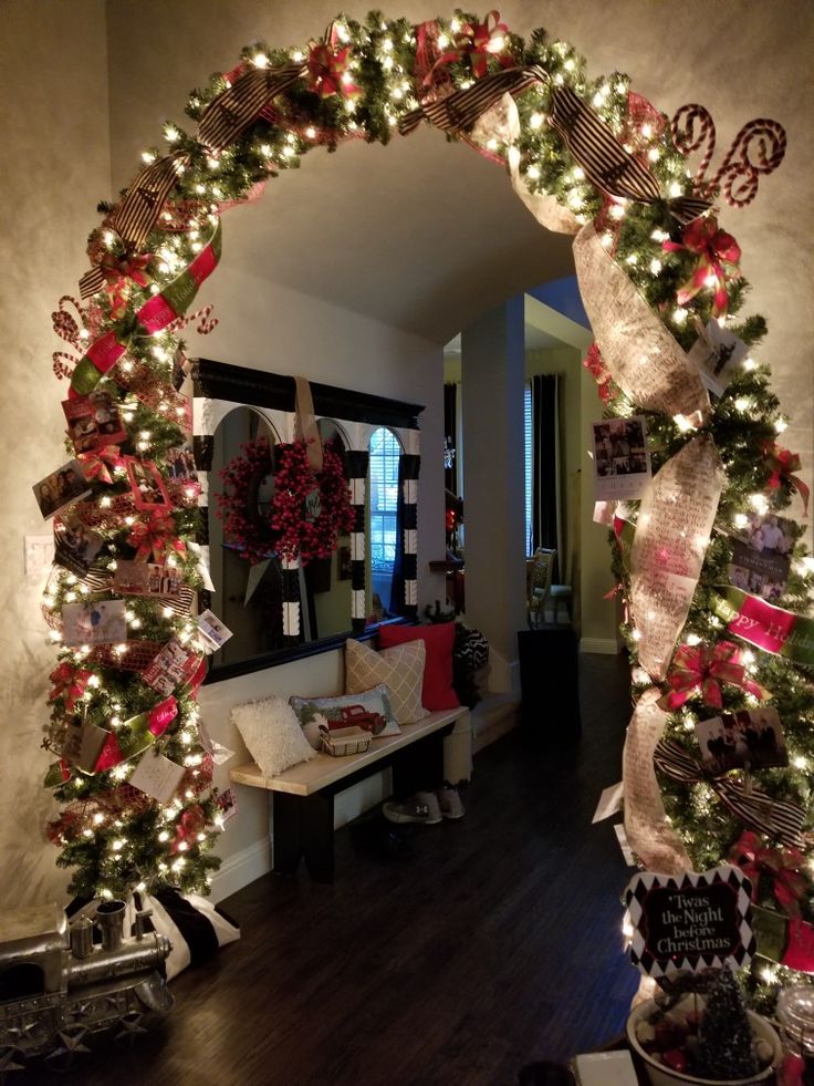 a christmas wreath is hanging on the wall in front of a mirror with lights around it