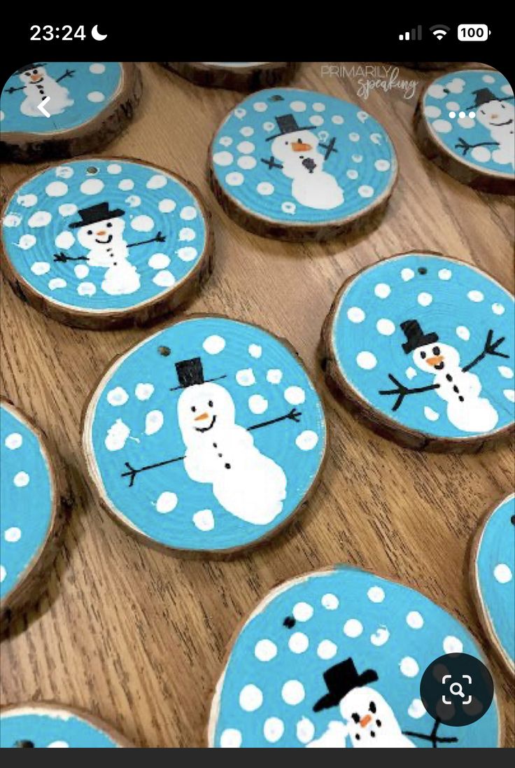 snowman cookies decorated with blue and white frosting on wooden slices, sitting on a table