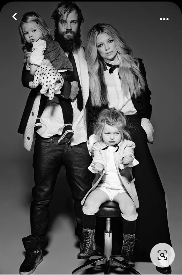 a man, woman and child are posing for a black and white photo in front of a gray background