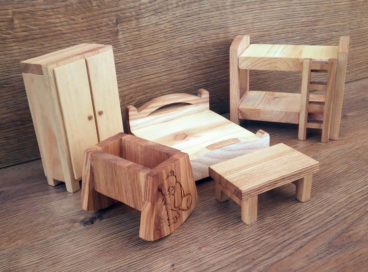 small wooden toys sitting on top of a wooden floor next to a cabinet and chair