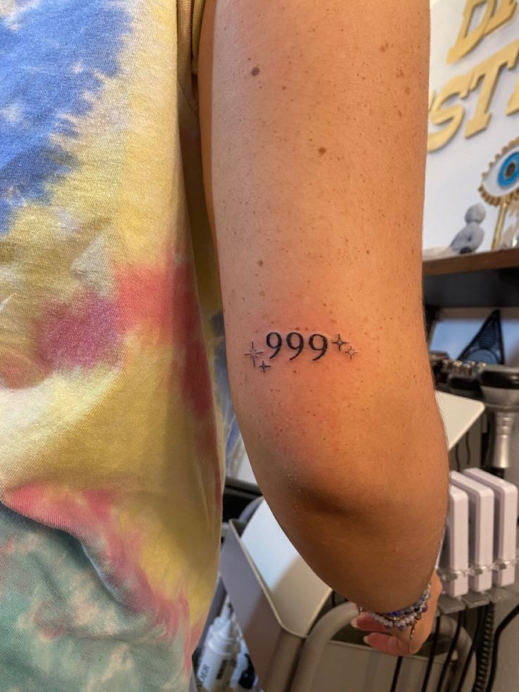 a person with a tattoo on their arm that reads 999 and has three stars