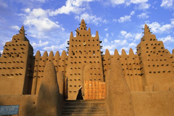 an adobe - style building in the desert against a blue sky with wispy clouds