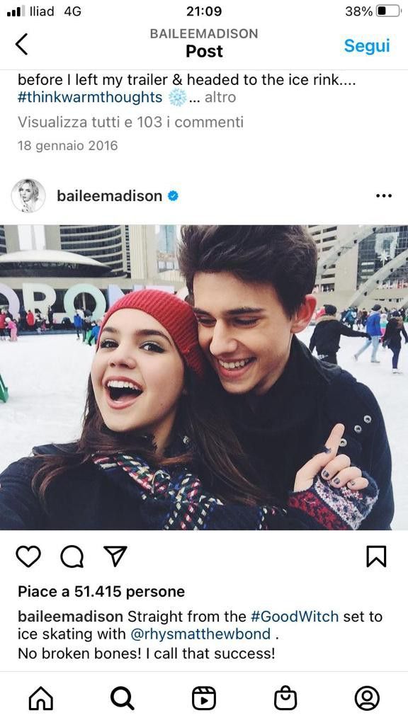 two people standing next to each other in front of a building with snow on the ground