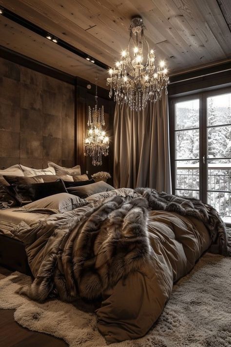 a bedroom with a large bed, chandelier and window overlooking the snow covered mountains