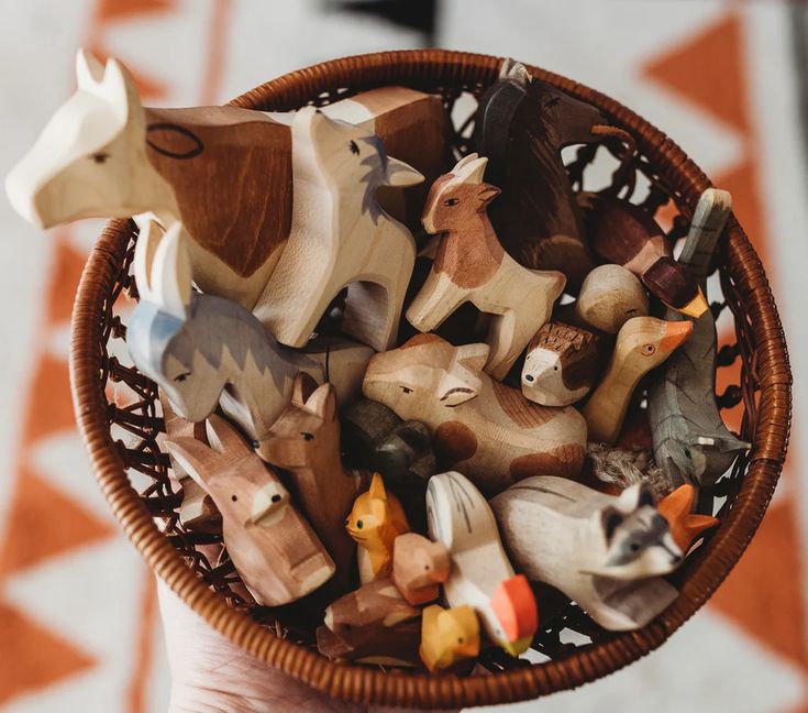 a basket filled with wooden toy animals on top of a table