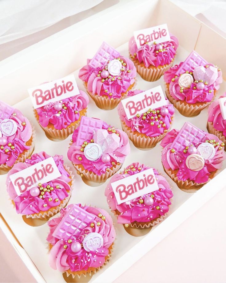 cupcakes with pink icing and decorations in a box