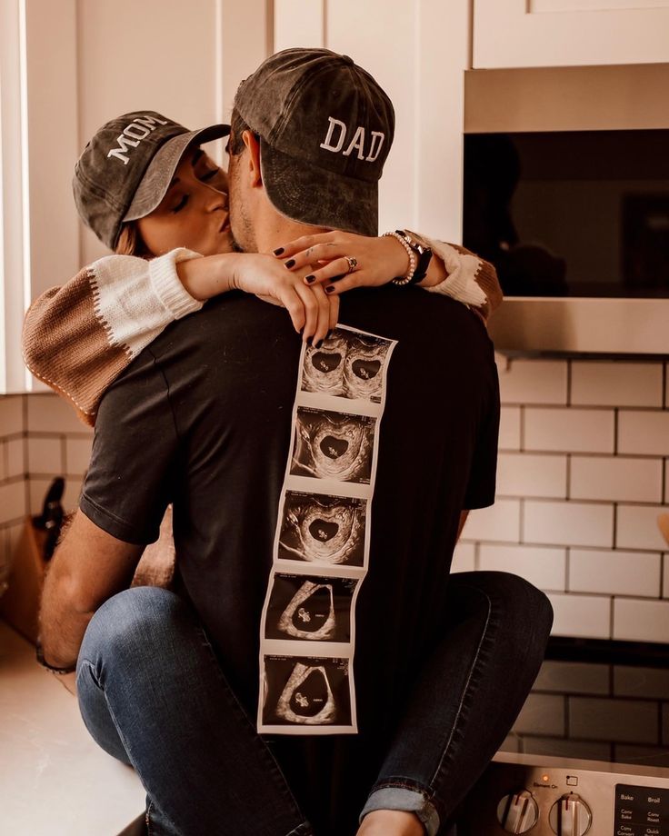 a man and woman sitting on the kitchen counter hugging each other's foreheads