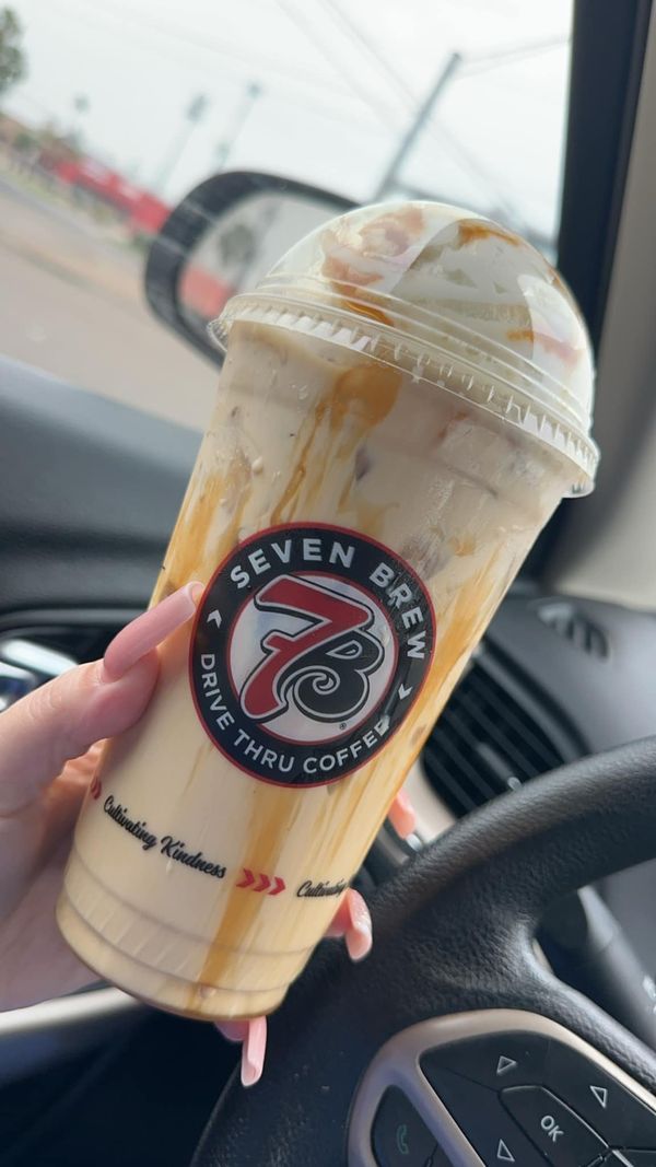 a woman holding up a cup of coffee in her car