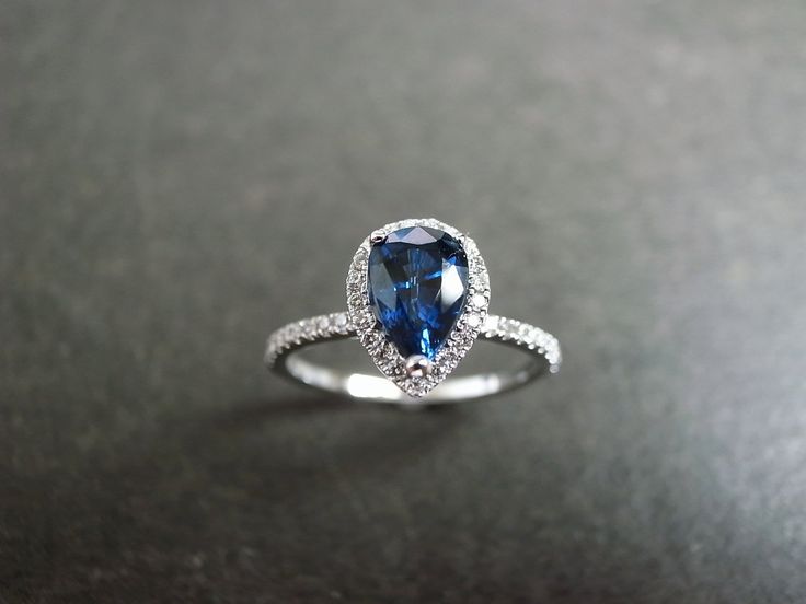 Pear Shaped Blue Sapphire Diamond Ring in White Gold - HN JEWELRY Elegant Sapphire Promise Ring With Center Stone, Elegant Sapphire Ring With Center Stone For Promise, Timeless Blue Jewelry For Wedding, Elegant Halo Ring With Gemstone And Round Cut, Elegant Sapphire Ring With Halo Setting As Gift, Elegant Halo Ring With Round Cut Gemstone, Dazzling Sapphire Ring With Halo Setting For Wedding, Dazzling Sapphire Wedding Ring With Accent Stones, Fine Jewelry Pear-shaped Sapphire Ring With Halo Setting