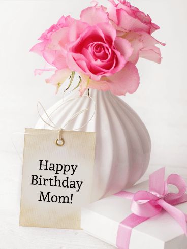 a white vase filled with pink flowers next to a card saying happy birthday mom on it