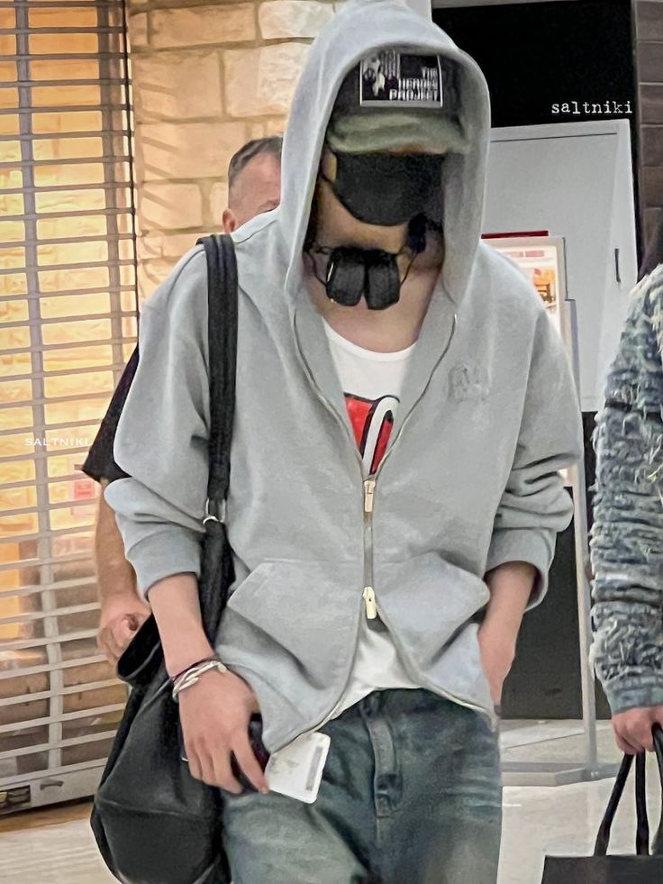 a man wearing a gas mask and holding a bag in his hand while walking through an airport