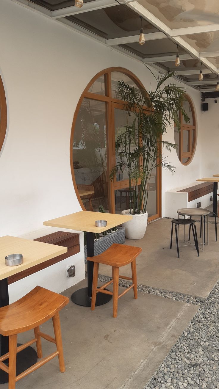 an empty restaurant with tables and stools in front of large round windowed windows