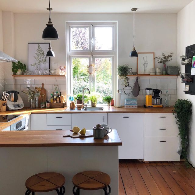 a kitchen with two stools in front of the counter and an open window over the sink