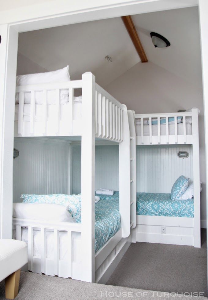 two bunk beds in a room with white walls and carpeted flooring, one is blue and the other is white