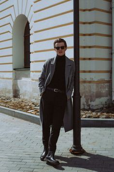 a man standing next to a pole in front of a building