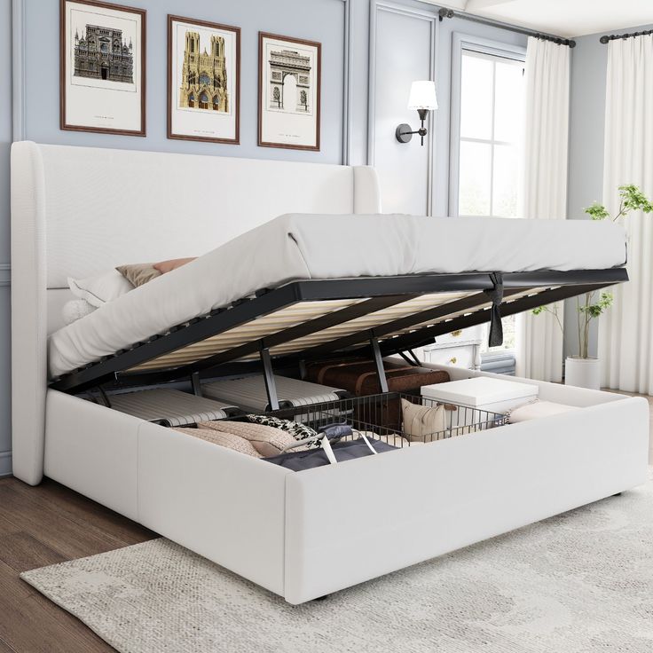 a white bed with a pull out mattress and storage underneath it in a living room