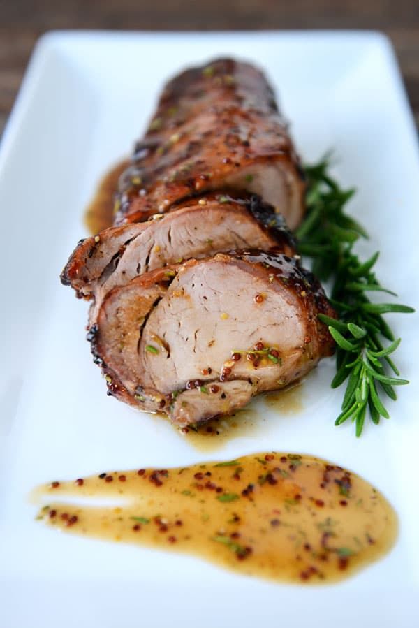 a white plate topped with meat covered in sauce and garnished with green herbs