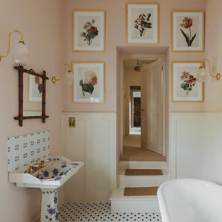 a bathroom with pink walls and pictures on the wall