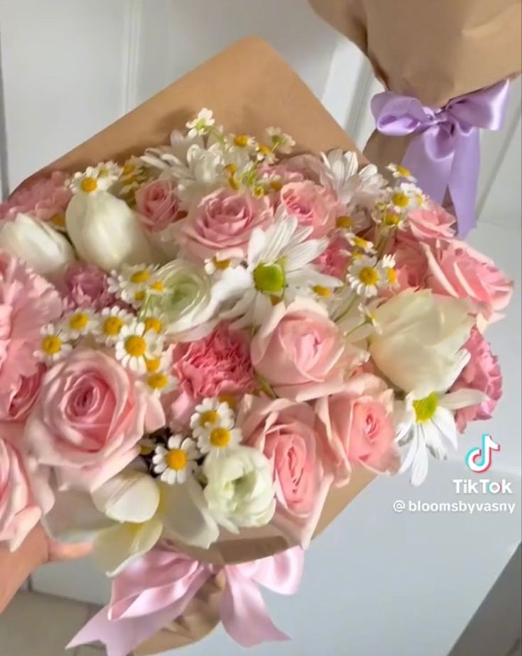 a woman holding a bouquet of pink and white flowers