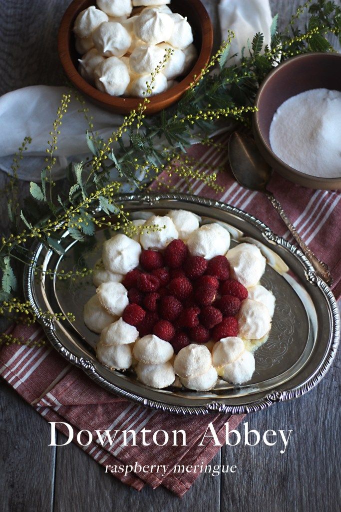 a plate with marshmallows and raspberries on it next to other dishes