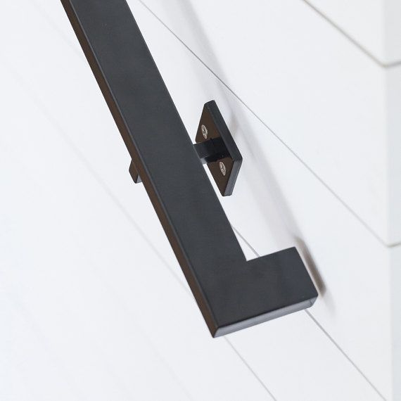 a close up of a door handle on a white wall with black hardware and wood planks