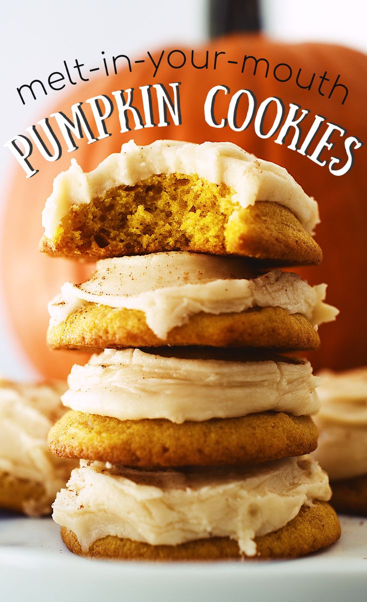 pumpkin cookies stacked on top of each other with frosting and an orange pumpkin in the background