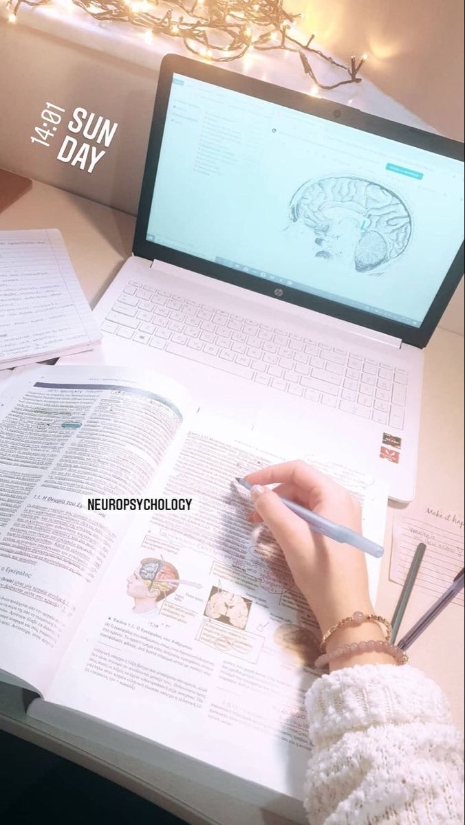 a person is writing on a book with a laptop in front of them and an open notebook next to it