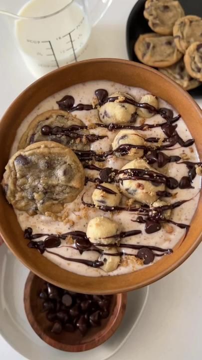 a bowl filled with ice cream and cookies on top of a white table next to chocolate chips