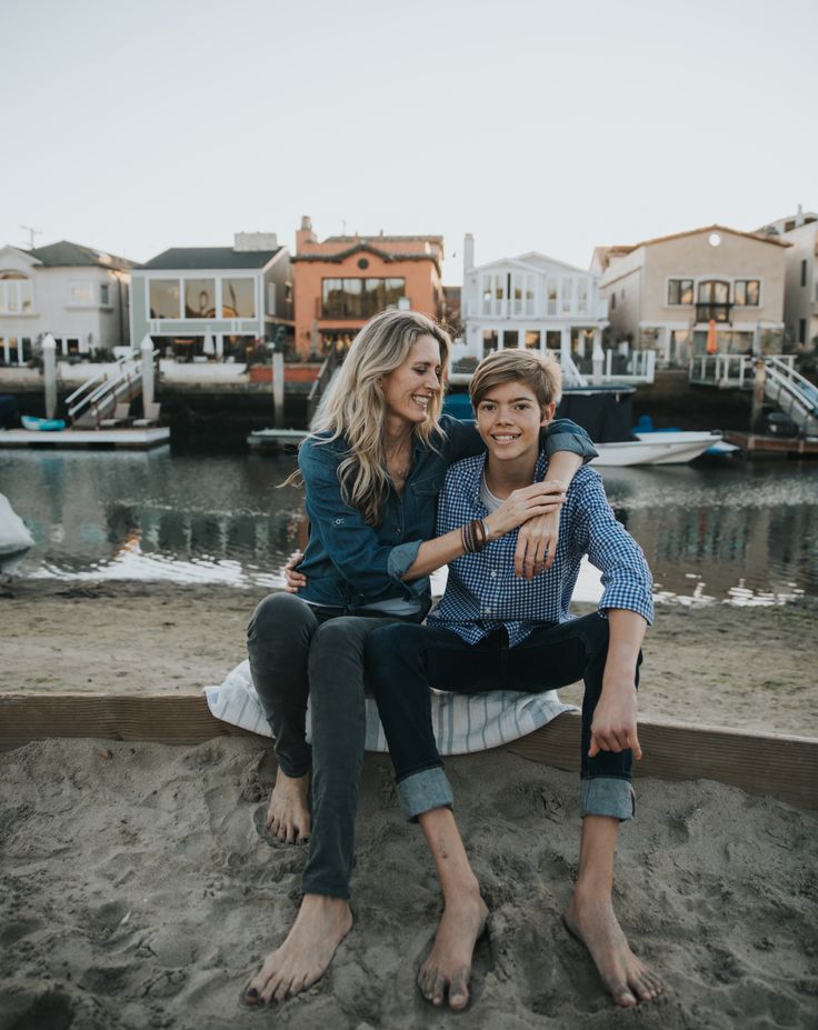 a woman sitting on top of a man's lap in front of a body of water