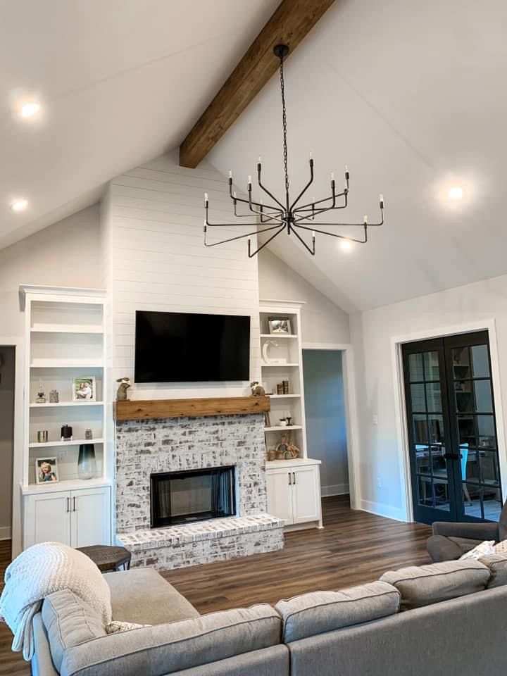 a living room with couches and a television on the wall in front of a fireplace