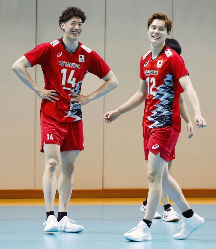 two men in red uniforms standing on a basketball court with their arms around each other