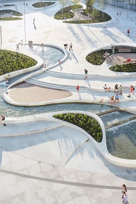 an aerial view of people walking and playing in the water at a public park with fountains