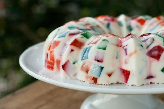 a cake that is sitting on top of a white plate and has colorful icing all over it