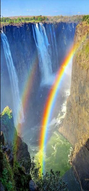 a rainbow in the middle of a waterfall with water falling off it's sides