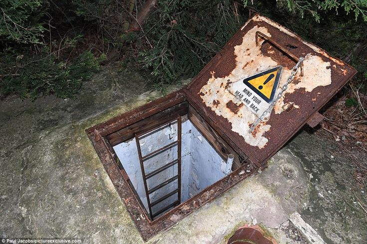 an old outhouse with a warning sign on the door and window is sitting in front of some trees