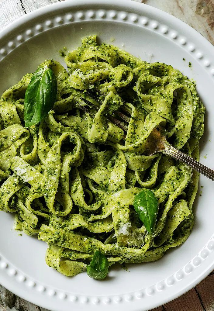 a white bowl filled with pesto pasta on top of a table