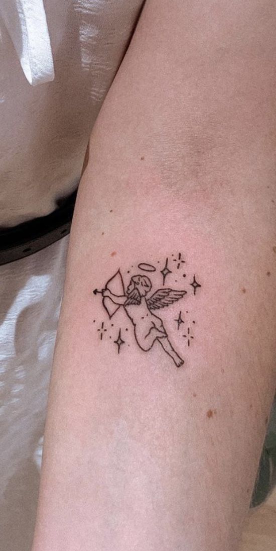 a small tattoo on the arm of a woman with an angel and stars around her