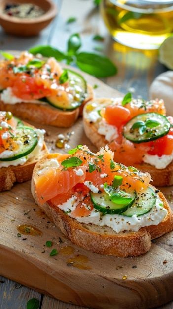 several pieces of bread with various toppings on them sitting on a cutting board next to wine glasses