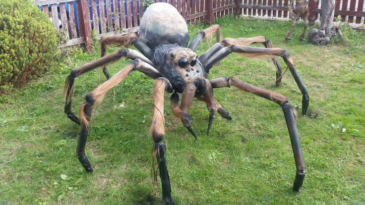 a large spider statue sitting on top of a lush green field