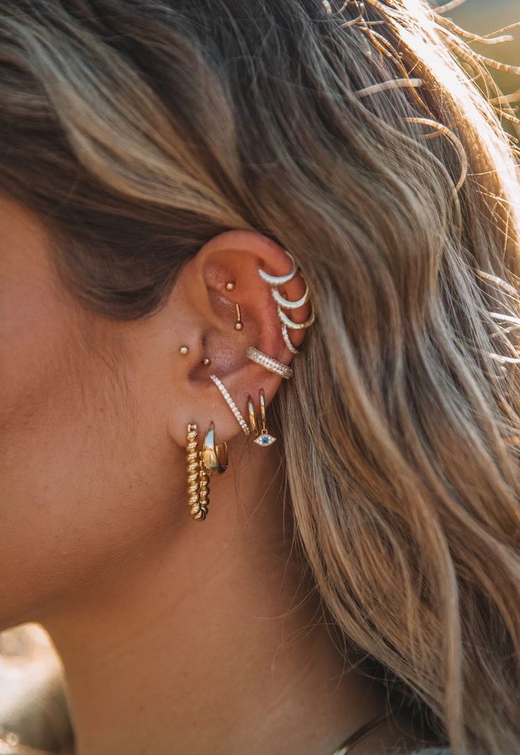 a woman wearing ear piercings with pearls on her ears and gold colored beads in the middle