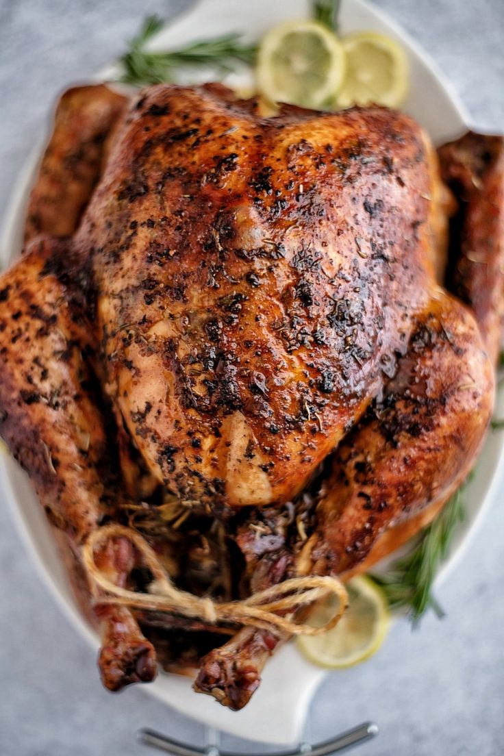 a roasted chicken on a plate with lemons and herbs