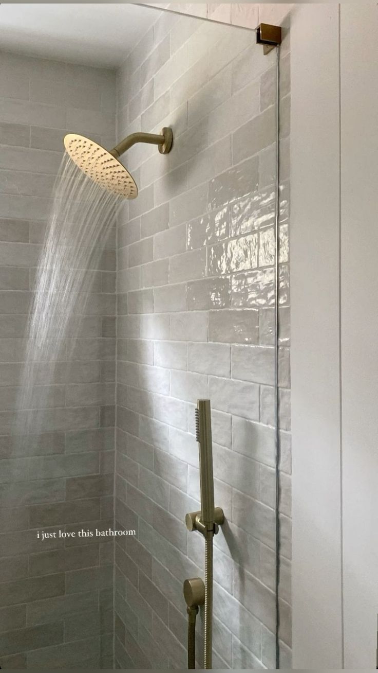 a shower head and thermostaer in a white tiled bathroom with gray tile