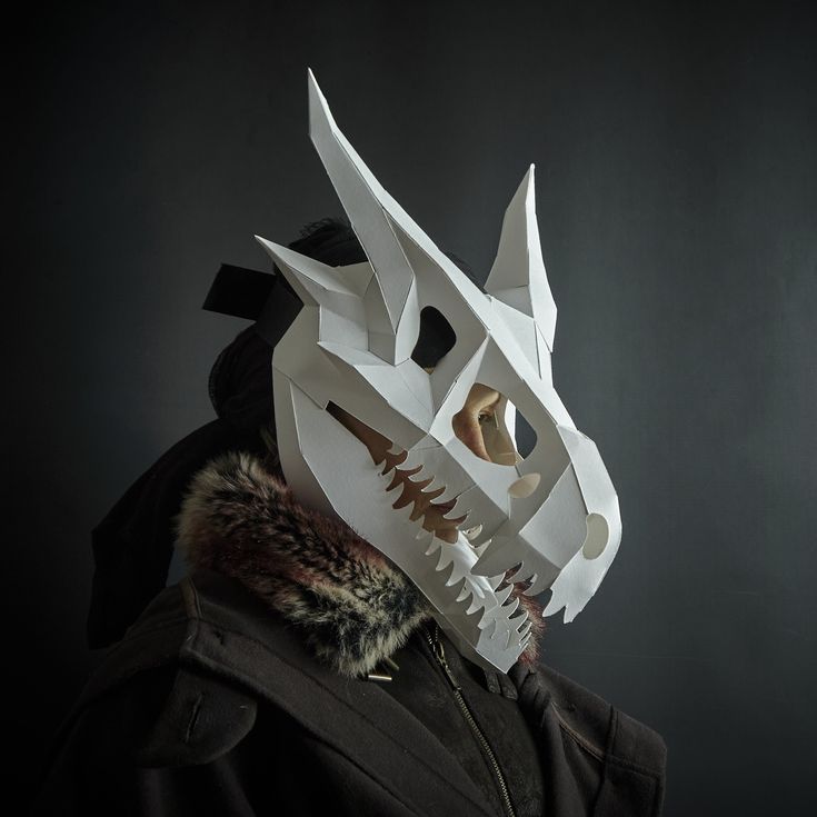 a man wearing a white mask with spikes on it's face and a fur collar around his neck