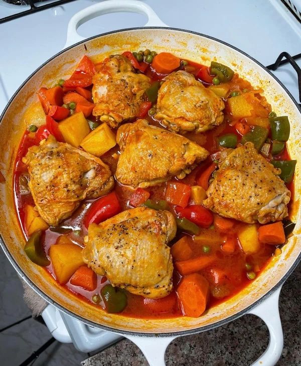 a pan filled with chicken and vegetables on top of a stove